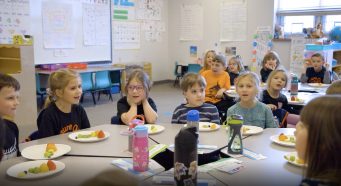 Kids eating snack around small classroom table