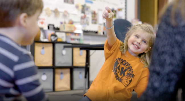 Smiling girl wearing orange Oakfield 4K t-shirt